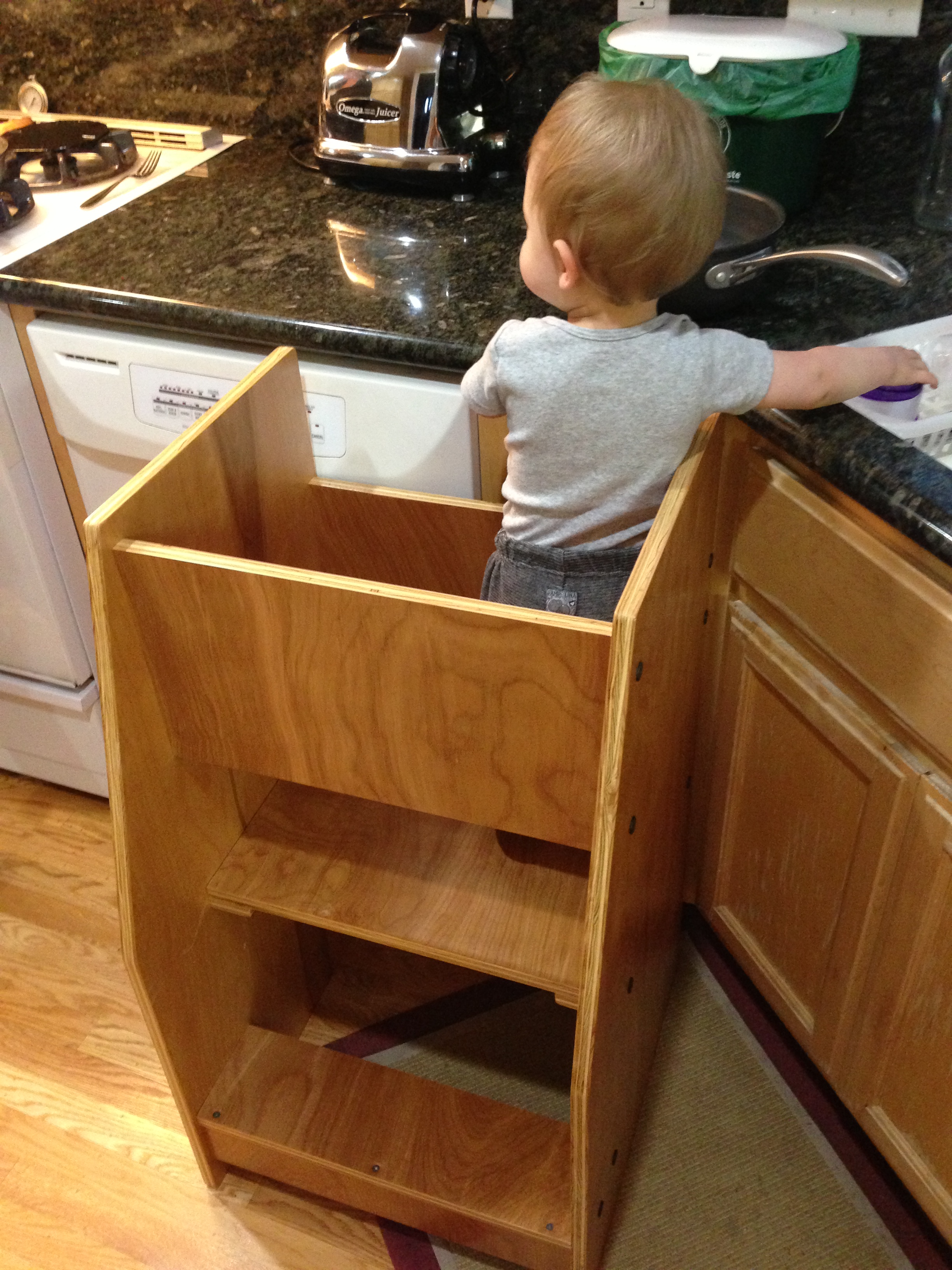 kid in the tower by the sink